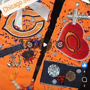 Może przedstawiać: Pomarańczowe skarpetki z ozdobami, w tym logo Chicago Bears, krzyżem i różnymi elementami dekoracyjnymi. Tekst "Chicago Stand up!!" jest wyświetlany na białym banerze. Skarpetki są ozdobione koralikami i cekinami.