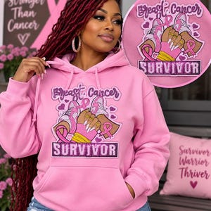 Puede incluir: Una sudadera con capucha de color rosa claro que presenta un parche gráfico con el texto Breast Cancer SURVIVOR. El diseño incluye ilustraciones de zapatillas, cintas rosas y manos con uñas manicuradas. La prenda tiene mangas largas.