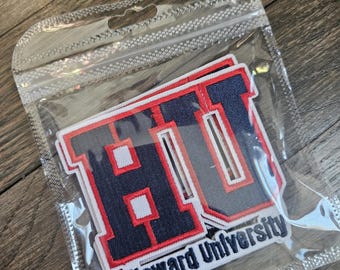 Peut inclure: Un ensemble d'écussons brodés dans un sachet en plastique transparent. Les écussons présentent les lettres HU en bleu marine avec une bordure rouge et blanche, et le texte Howard University en bleu marine sur fond blanc.