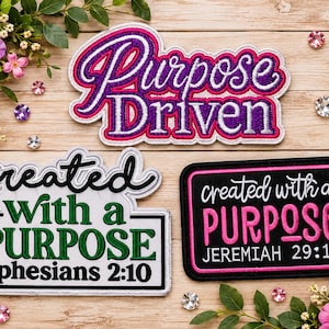 May include: Three embroidered patches with text. The top patch reads Purpose Driven in purple and silver. The bottom left patch reads created with a PURPOSE ephesians 2:10 in green and black. The bottom right patch reads created with a PURPOSE JEREMIAH 29:11 in pink and white on a black background.