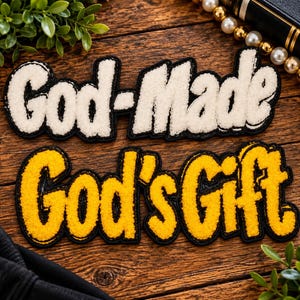 May include: Two chenille patches with black borders. The top patch is cream-colored and features the text "God-Made" in a bold, cursive font. The bottom patch is bright yellow and features the text "God's Gift" in a matching bold, cursive font.