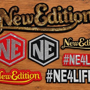 Può includere: Una collezione di toppe ricamate con il testo New Edition in paillettes dorate, una scritta dorata più piccola e due toppe esagonali con le lettere NE in argento. Sono incluse anche due toppe rettangolari con il testo #NE4LIFE.