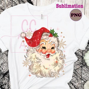 Pu&ograve; includere: Un'illustrazione in stile vintage del viso di Babbo Natale con un cappello rosso, una barba bianca e guance rosate. L'immagine &egrave; circondata da fiocchi di neve dorati e glitter rosa e dorati.