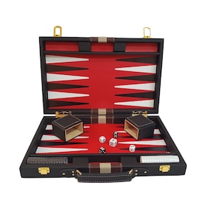 May include: Open black backgammon set with red and white playing surface. Includes two brown dice cups, dice, and a handle. The set is made of leather and has gold-colored hardware.