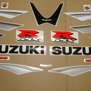 Puede incluir: Un conjunto de calcomanías para motocicletas con el logotipo de Suzuki, GSX-R y 1000. Las calcomanías son de color negro, rojo, plateado y azul.
