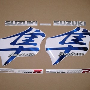 May include: A collection of Suzuki Hayabusa motorcycle decals. The decals include the Suzuki logo in silver, two large white and blue Hayabusa graphics, and smaller GSX 1300R decals. The graphics have a glossy finish.