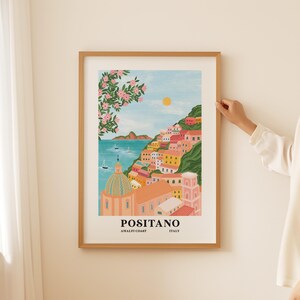 Puede incluir: Una ilustraci&oacute;n colorida de Positano, Italia, en la costa de Amalfi. La imagen presenta una iglesia rosa y blanca con una c&uacute;pula, edificios coloridos y un mar azul con barcos. El texto "Positano, Amalfi Coast, Italy" est&aacute; en la parte inferior de la imagen.