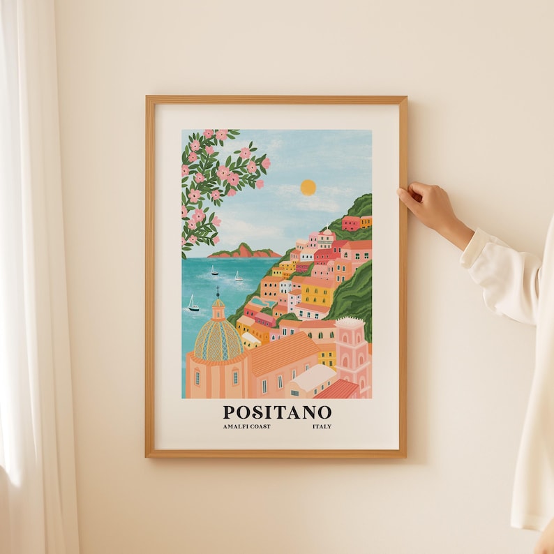 Puede incluir: Una ilustraci&oacute;n colorida de Positano, Italia, en la costa de Amalfi. La imagen presenta una iglesia rosa y blanca con una c&uacute;pula, edificios coloridos y un mar azul con barcos. El texto "Positano, Amalfi Coast, Italy" est&aacute; en la parte inferior de la imagen.