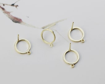 May include: Four gold-toned earring settings with a circular opening and a small loop on the bottom. The settings have a post on the top for attaching to an earring.