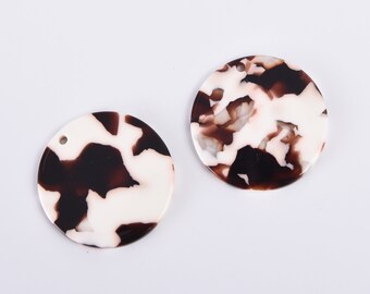 May include: Two round, white and brown patterned resin embellishments with a hole for hanging.