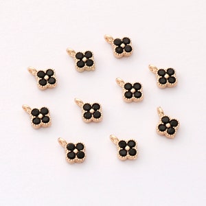May include: Ten gold-tone flower charms with black crystal accents. Each charm has a loop for attaching to jewellery.