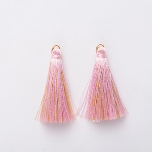 May include: Two pink and gold tassel charms with a gold loop at the top.
