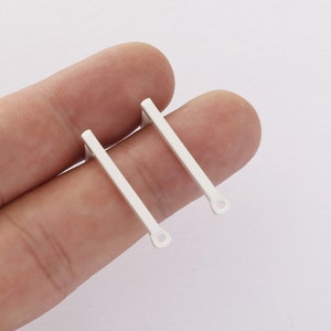 May include: Two silver earring blanks with a straight bar design and a small loop at the bottom.