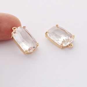 Puede incluir: Dos colgantes rectangulares de cristal transparente con engastes de metal dorado y anillas de salto.