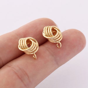 May include: A pair of gold-toned knot-shaped earrings with a dangling loop at the bottom.