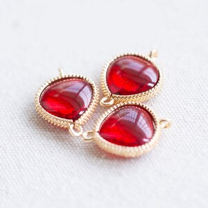 Peut inclure: Trois breloques en forme de larme en verre rouge avec des montures en métal doré. Les breloques ont un bord perlé et une boucle pour les attacher à des bijoux.
