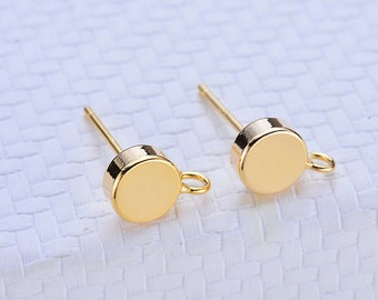 May include: Two gold-toned earring posts with a round disc and a small loop at the end.