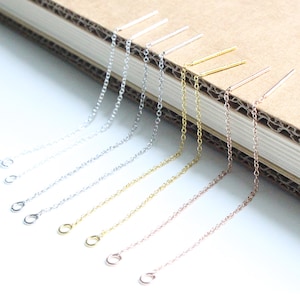 May include: A set of six earring chain extenders in silver, gold, and rose gold. Each extender features a delicate chain with a small loop at the end.
