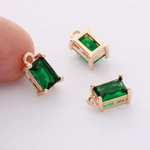 May include: Three gold-toned pendant charms with emerald green rectangular glass stones. Each charm has a loop at the top for attaching to a necklace or bracelet.