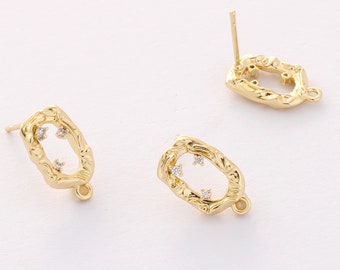 May include: Gold-tone earrings with a textured oval shape and small clear rhinestones. The earrings have a post back.