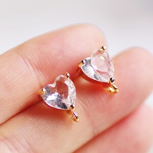 May include: Two gold-tone heart-shaped charms with clear crystal accents. Each charm has a loop for attaching to jewelry.