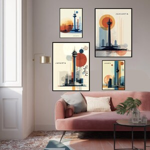May include: A set of four framed art prints featuring stylized illustrations of Jakarta landmarks. Each print showcases a tower with a circular sun or moon design, using a palette of orange, blue, and beige. The word "JAKARTA" is printed on each artwork.