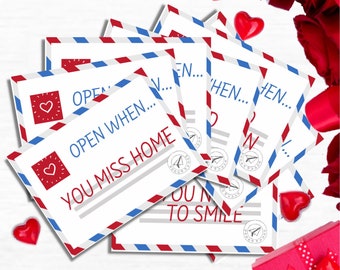 May include: A set of six envelopes with red and blue stripes and the text "Open When..." followed by different phrases. The envelopes are arranged in a pile with a red ribbon and a small gift box with a red bow.