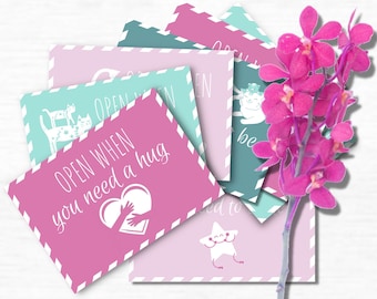 Può includere: Un set di 52 carte rosa, blu e verdi con il testo "OPEN WHEN LETTERS" e "Care Package for Mom" in alto. Le carte hanno messaggi diversi, come "OPEN WHEN you need a hug". Le carte sono decorate con cuori, stelle e altre illustrazioni carine. Il testo "CREATE! SURPRISE! LOVE!" è su una piccola busta con cuori intorno.