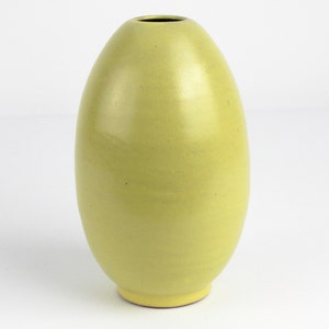 Könnte beinhalten: Eine gelbe Keramikvase in Form eines Eies. Die Vase hat eine glatte, glänzende Oberfläche.