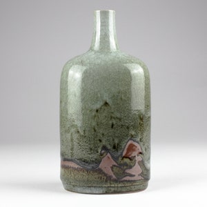 May include: A ceramic vase with a light green glaze and brown and pink accents. The vase has a rounded body and a narrow neck.