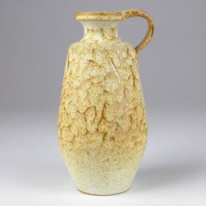 May include: A ceramic pitcher with a textured, leaf-like design in shades of brown and cream.