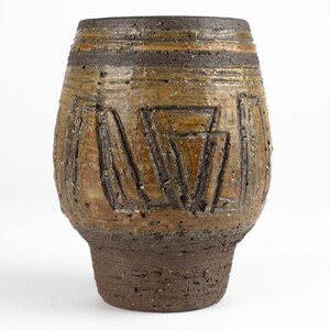 Könnte beinhalten: Eine braune und beigefarbene Keramikvase mit geometrischem Muster. Die Vase hat einen breiten Boden und einen schmalen Hals.