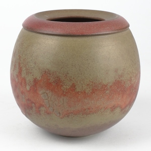 May include: A round ceramic vase with a brown and red glaze. The vase has a wide mouth and a rounded bottom.