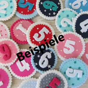 Könnte beinhalten: Ein Satz Filz-Kreise mit den Zahlen 1 bis 9, jeder mit einer anderen Farbe und einem anderen Muster. Die Kreise sind in einem Halbkreis angeordnet, mit dem Wort "Beispiele" in der Mitte.