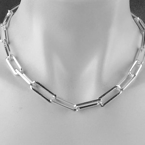 May include: A silver chain necklace with a simple, rectangular link design.