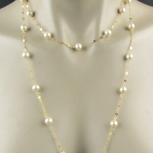 May include: A layered necklace featuring faux pearls and gold-colored chain. The necklace has two strands, one shorter and one longer, both adorned with evenly spaced, round, white pearls. The gold chain adds a touch of elegance to this classic jewelry piece.
