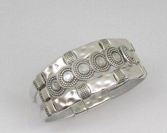 May include: Silver bracelet with three rows of decorative circles. Each circle has a textured design.