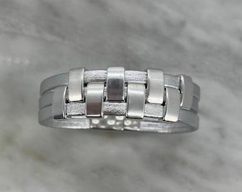 May include: A silver leather bracelet with a woven design. The bracelet has a magnetic clasp.