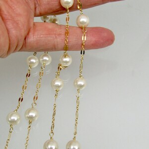 May include: Elegant pearl necklaces with gold chains. The necklaces feature large, round, creamy white pearls strung on delicate gold-colored chains. The chains have a repeating pattern of small, flat, gold links.