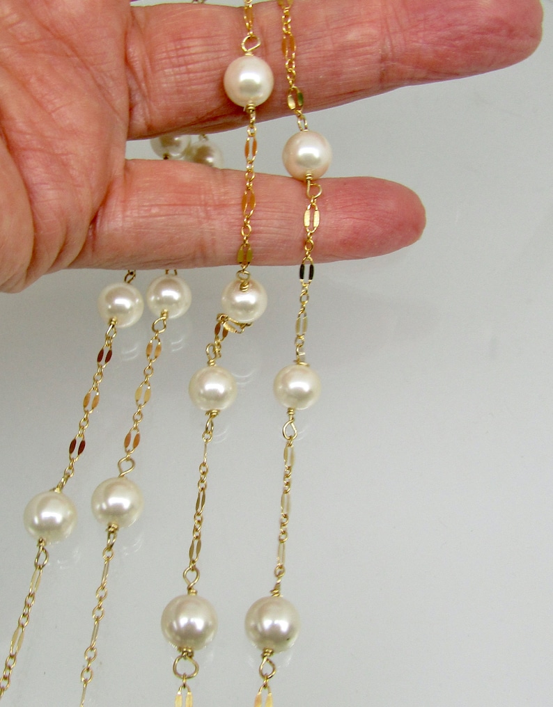 May include: Elegant pearl necklaces with gold chains. The necklaces feature large, round, creamy white pearls strung on delicate gold-colored chains. The chains have a repeating pattern of small, flat, gold links.