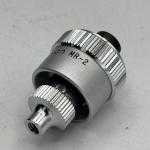May include: A silver metal camera lens adapter with the text "Canon MR-2" printed on the side.