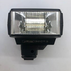May include: A black Metz 32CT3 flash unit with a clear plastic diffuser. The flash unit has a standard hot shoe mount.