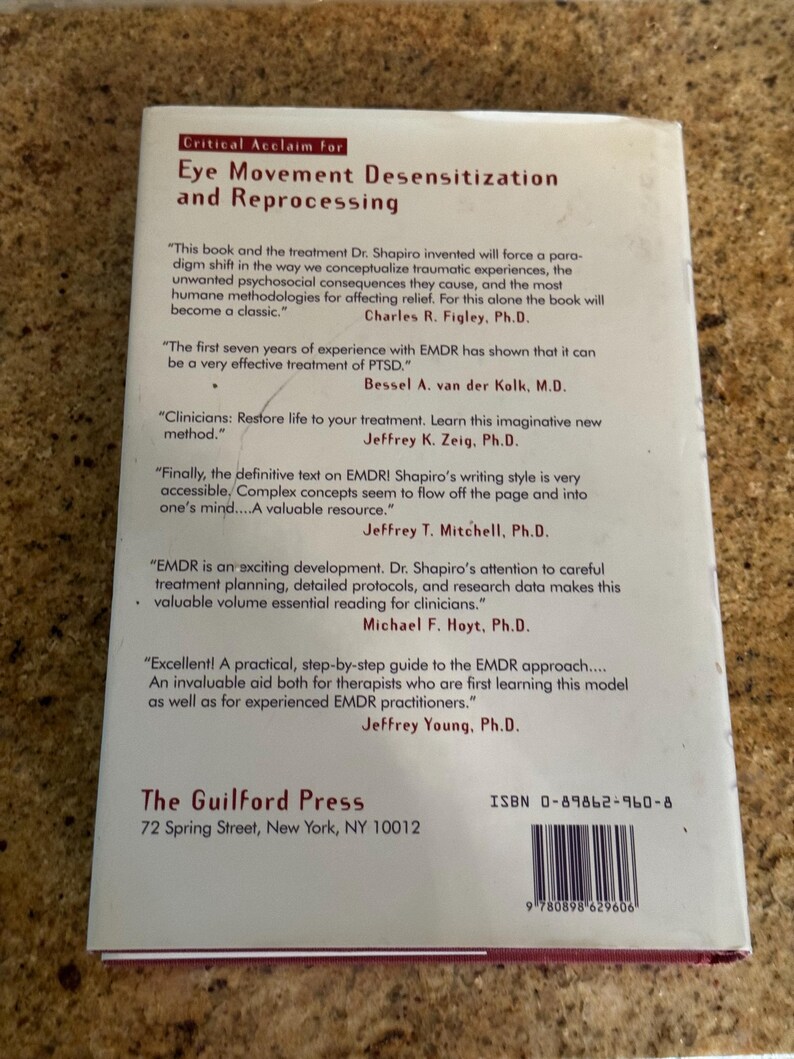 May include: The back cover of a book titled "Eye Movement Desensitization and Reprocessing." The cover is white with black text, including quotes and author names. The Guilford Press logo and ISBN are also visible.