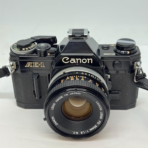 May include: A set of three ceramic canisters with lids, featuring a geometric pattern in shades of blue, white, and gray. The canisters vary in size, with the largest approximately 8 inches tall.