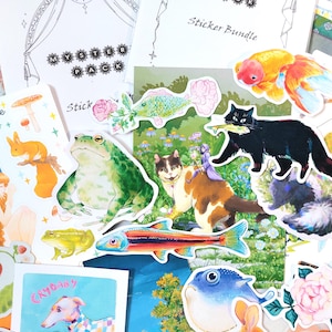 Peut inclure: Une collection d'autocollants colorés avec diverses illustrations fantaisistes. Comprend une grenouille verte, un chat noir avec un poisson, un chat avec une fée et un poisson rouge. Comprend également des feuilles d'autocollants avec du texte comme "Mystery Pack" et "Sticker Bundle".