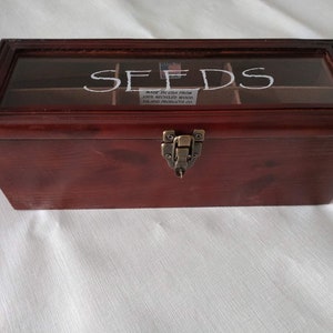 May include: A wooden box with a glass top and a latch. The box is divided into compartments and labeled "SEEDS". The box is made in the USA from 100% recycled wood.