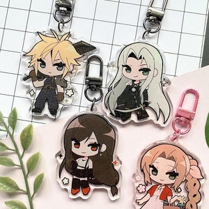 Puede incluir: Cuatro llaveros acrílicos con personajes chibi, cada uno con un cierre metálico. Los personajes tienen cabello rubio, plateado, castaño y rojo, y visten diferentes atuendos. Cada llavero tiene un efecto brillante y detalles en forma de estrella.