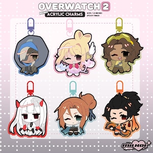 May include: Six Overwatch 2 mini acrylic charms with epoxy finish, each 4cm tall. The charms feature stylized chibi characters including Ana, Mercy, Tracer, Kiriko, Brigitte, and Hanzo, each attached to a coloured plastic lobster clasp.