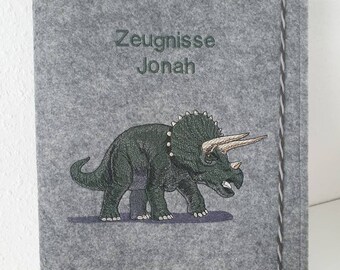 May include: Gray felt folder with a dinosaur embroidery and the text "Zeugnisse Jonah".