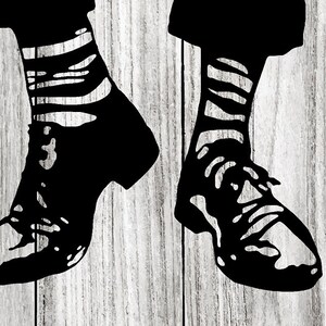 May include: A pair of black shoes with white striped socks. The shoes are on a wooden surface.